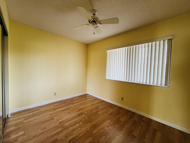 empty room with a textured ceiling, ceiling fan, and wood-type flooring