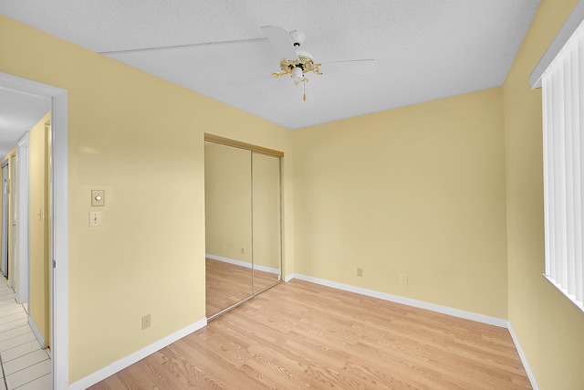 unfurnished bedroom with light wood-style floors, baseboards, a ceiling fan, and a closet