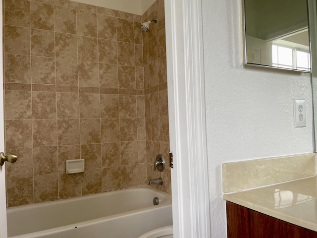 bathroom featuring tiled shower / bath combo and vanity