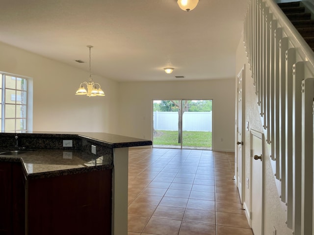 kitchen featuring sink, an inviting chandelier, hanging light fixtures, light tile patterned floors, and dark brown cabinets