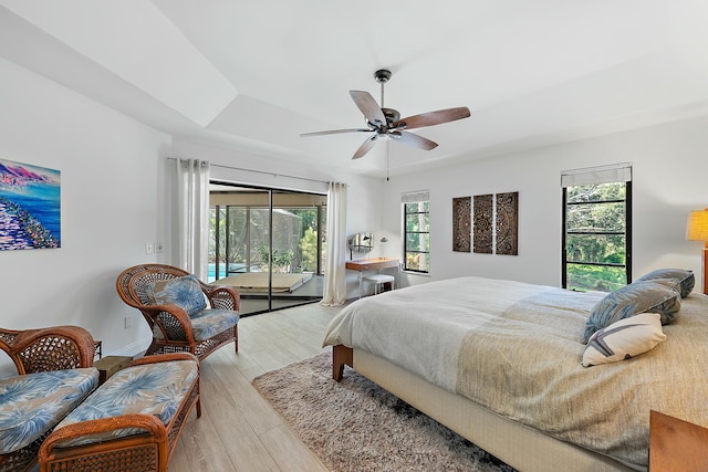 bedroom featuring a raised ceiling, ceiling fan, access to outside, and light hardwood / wood-style floors