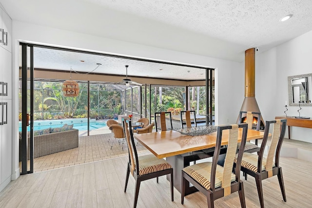 dining area featuring a textured ceiling, light hardwood / wood-style flooring, and a wood stove