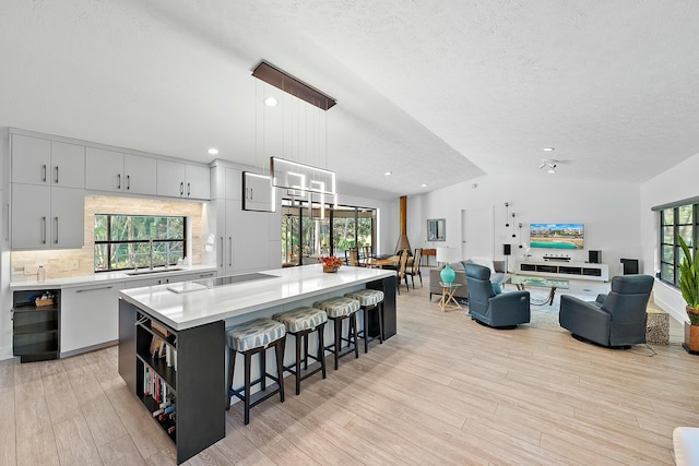 kitchen with lofted ceiling, decorative light fixtures, a center island, a kitchen breakfast bar, and beverage cooler