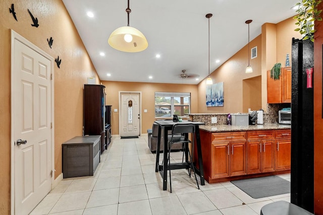 kitchen featuring decorative light fixtures, stone counters, a kitchen breakfast bar, and tasteful backsplash