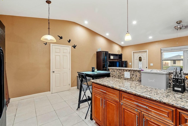 kitchen with hanging light fixtures, vaulted ceiling, and light stone counters