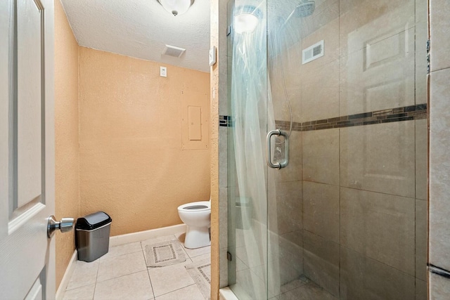 bathroom with a textured ceiling, walk in shower, tile patterned flooring, and toilet