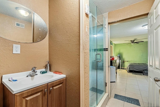 bathroom featuring a textured ceiling, tile patterned flooring, ceiling fan, a shower with door, and vanity