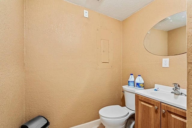 bathroom featuring toilet, vanity, a textured ceiling, and electric panel