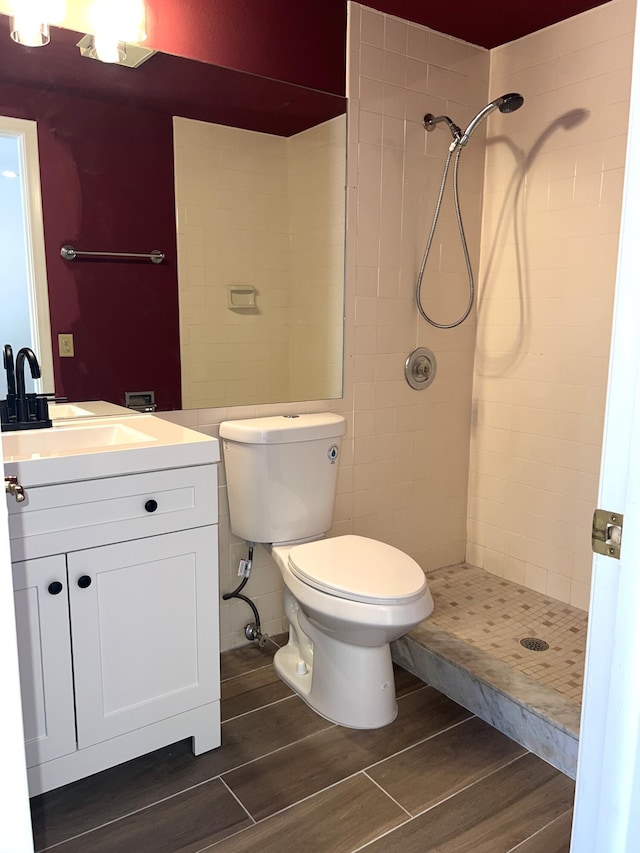 bathroom with toilet, vanity, and a tile shower