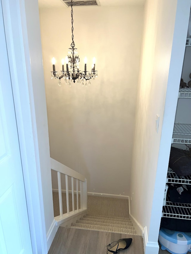 stairway with an inviting chandelier and hardwood / wood-style flooring