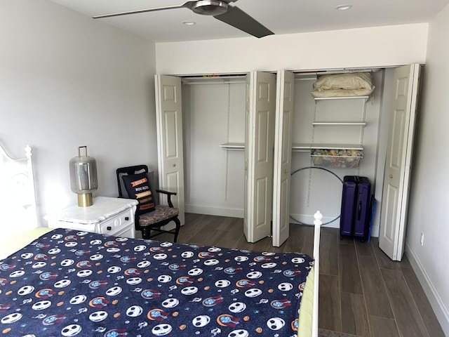 bedroom featuring ceiling fan, multiple closets, and dark hardwood / wood-style flooring