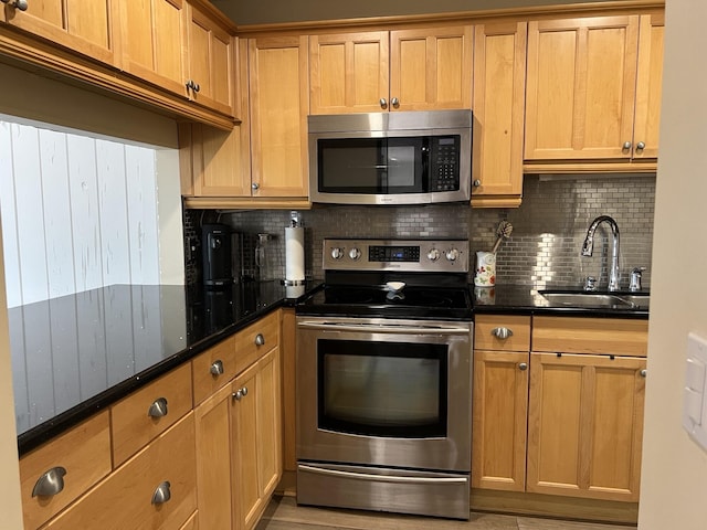 kitchen featuring decorative backsplash, dark stone counters, sink, and stainless steel appliances