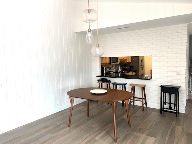 dining space featuring vaulted ceiling and dark hardwood / wood-style floors