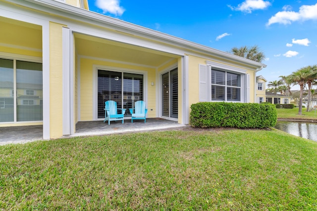 view of exterior entry with a yard and a patio