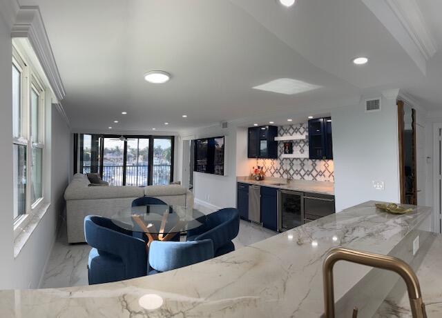 living area with marble finish floor, crown molding, recessed lighting, visible vents, and wet bar