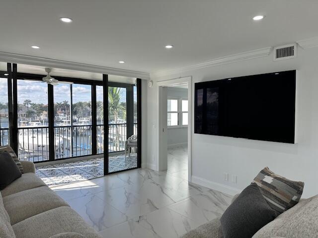 living area with visible vents, baseboards, crown molding, and recessed lighting