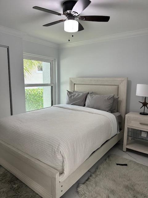 bedroom featuring ceiling fan, dark colored carpet, and ornamental molding