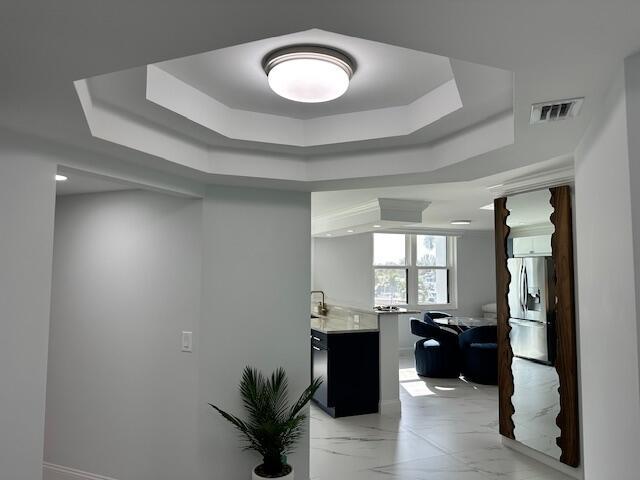 bar with stainless steel fridge, a raised ceiling, visible vents, and marble finish floor