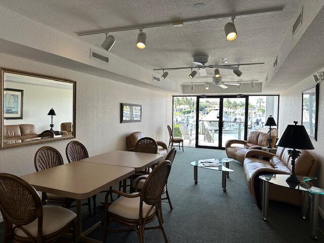 carpeted dining room with a wealth of natural light, visible vents, a textured wall, and a textured ceiling