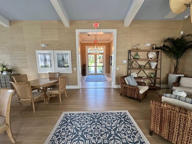 interior space with french doors, a notable chandelier, wood finished floors, beamed ceiling, and baseboards