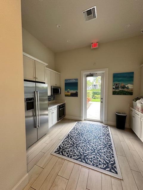 kitchen featuring wood finish floors, visible vents, light countertops, appliances with stainless steel finishes, and white cabinets