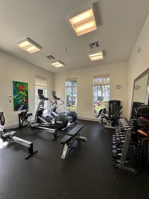 gym featuring visible vents, a textured ceiling, and baseboards