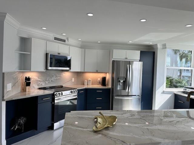 kitchen with appliances with stainless steel finishes, blue cabinets, white cabinetry, and light stone counters