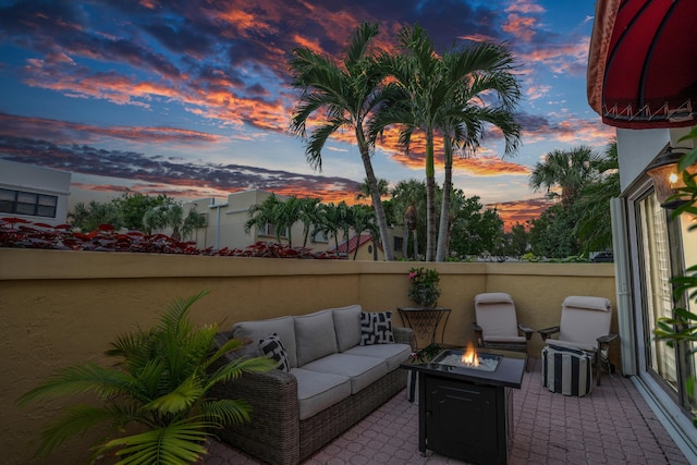 patio terrace at dusk with an outdoor living space with a fire pit