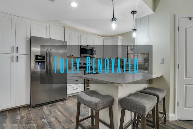 kitchen with white cabinets, stainless steel appliances, dark wood-style floors, decorative backsplash, and a breakfast bar