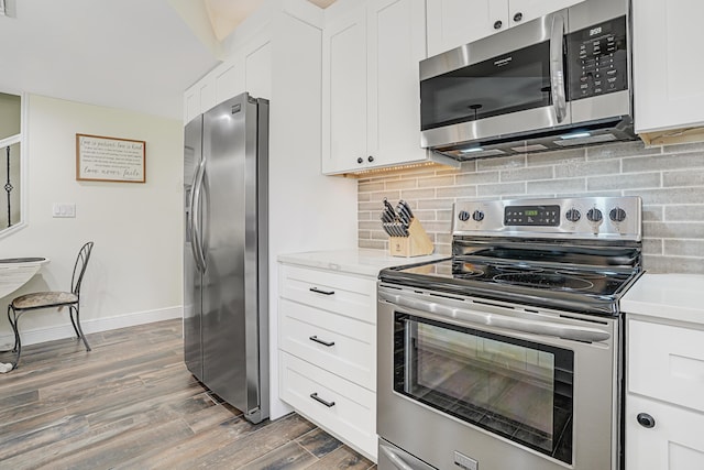 kitchen featuring tasteful backsplash, white cabinetry, dark hardwood / wood-style flooring, stainless steel appliances, and light stone countertops