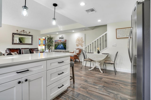 kitchen with pendant lighting, stainless steel fridge, white cabinetry, dark hardwood / wood-style floors, and light stone counters