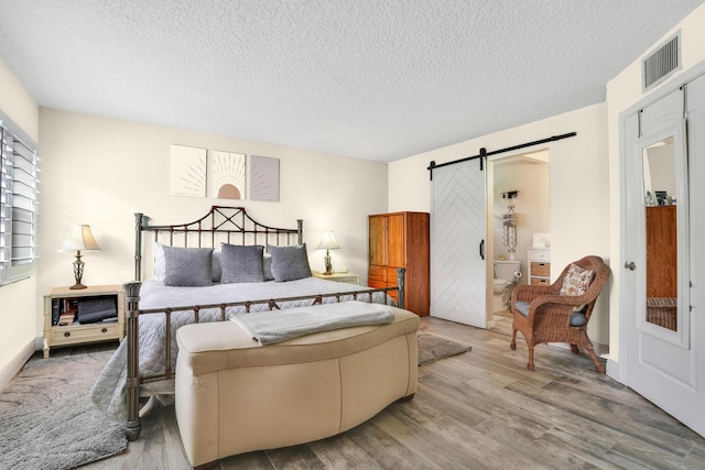 bedroom with hardwood / wood-style flooring, a barn door, and a textured ceiling