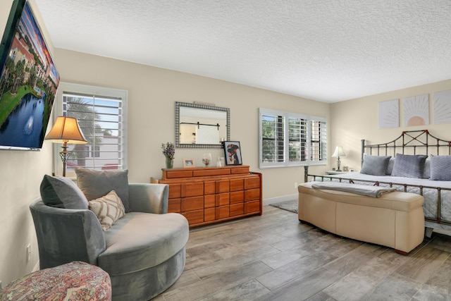 bedroom with baseboards, wood finished floors, and a textured ceiling