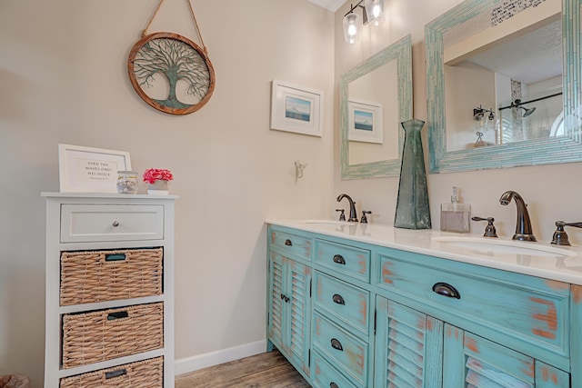 bathroom with walk in shower, double vanity, baseboards, and a sink