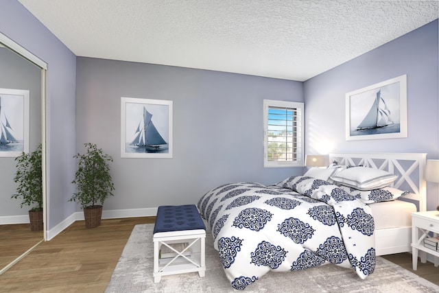 bedroom with baseboards, wood finished floors, and a textured ceiling