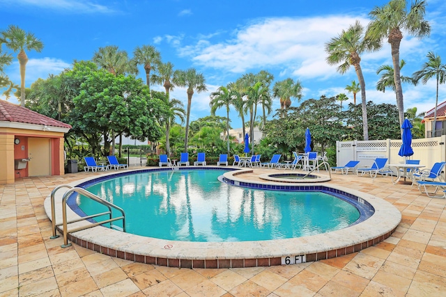community pool featuring a hot tub, a patio, and fence