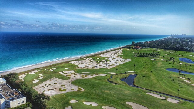 drone / aerial view with golf course view and a water view