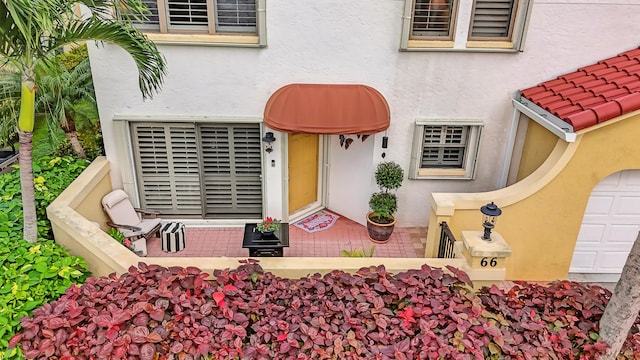 entrance to property with a garage and stucco siding