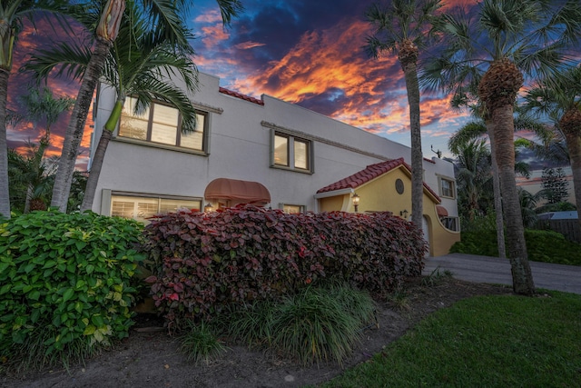 mediterranean / spanish home featuring stucco siding, an attached garage, and a tiled roof