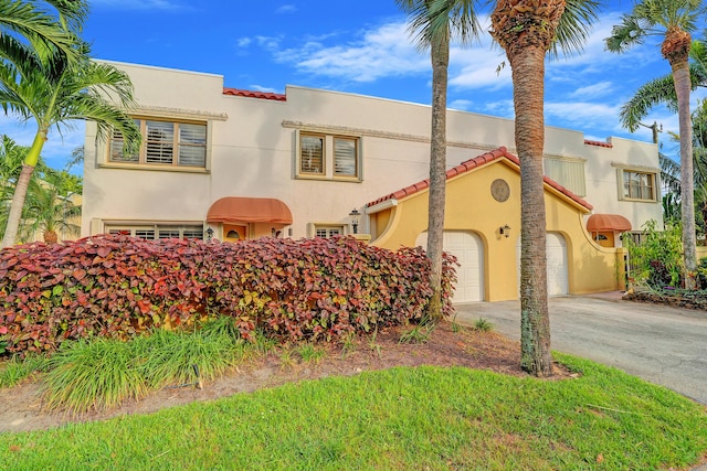 mediterranean / spanish house with a garage, driveway, a tiled roof, and stucco siding