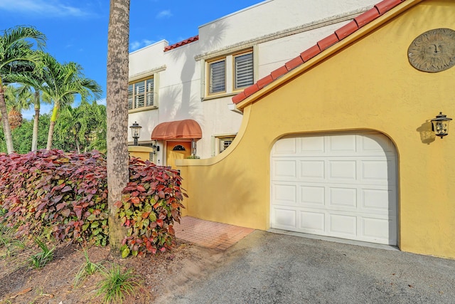 mediterranean / spanish home featuring stucco siding, a garage, and aphalt driveway