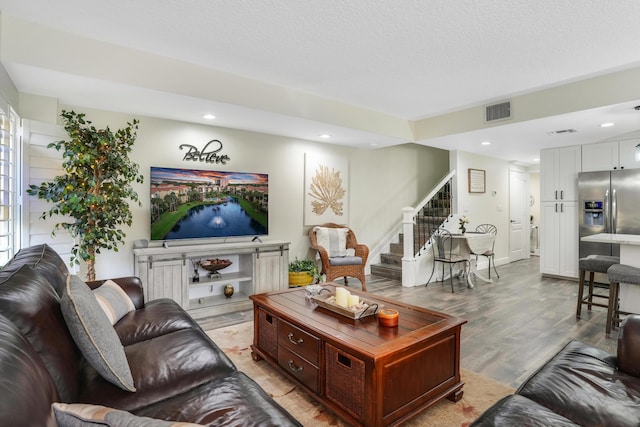 living area featuring light wood-type flooring, visible vents, recessed lighting, and stairway