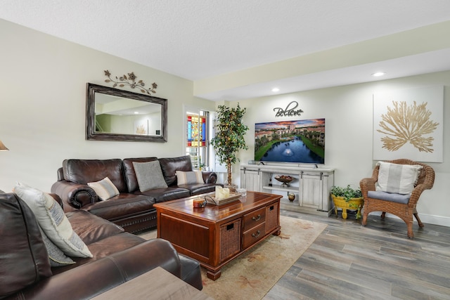living room featuring a textured ceiling, baseboards, recessed lighting, and light wood-style floors
