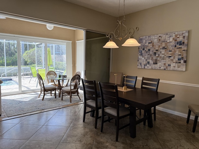 dining room featuring dark tile patterned flooring and a notable chandelier