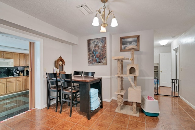 tiled dining space with a textured ceiling and a notable chandelier