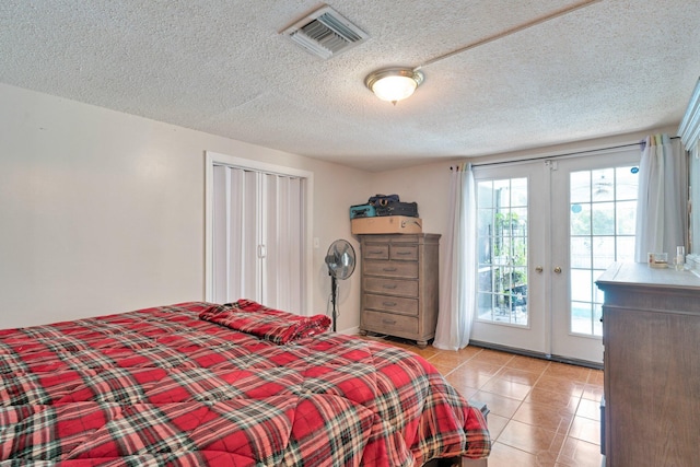 tiled bedroom with a textured ceiling, french doors, and access to exterior