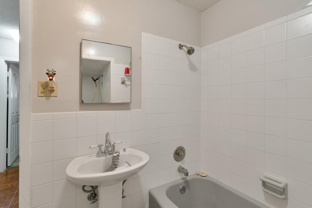 bathroom featuring tile walls, a textured ceiling, tiled shower / bath, and sink