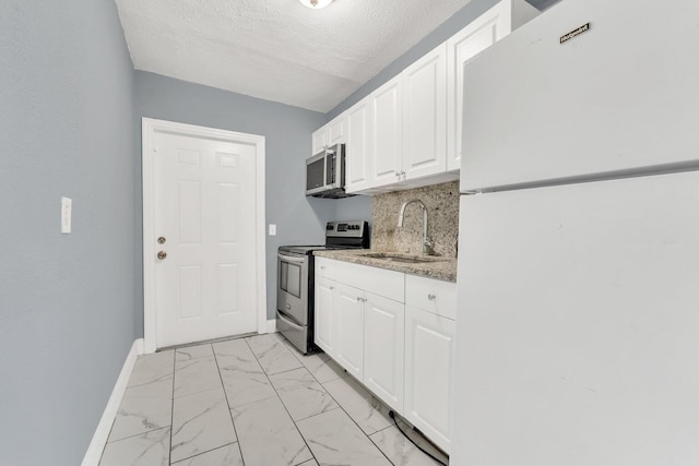 kitchen with stainless steel appliances, sink, a textured ceiling, white cabinetry, and backsplash