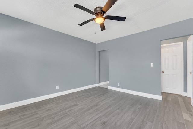 empty room featuring ceiling fan, a textured ceiling, and hardwood / wood-style flooring