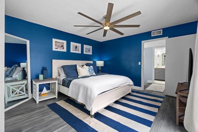 bedroom featuring dark wood-type flooring, a textured ceiling, ceiling fan, and ensuite bath